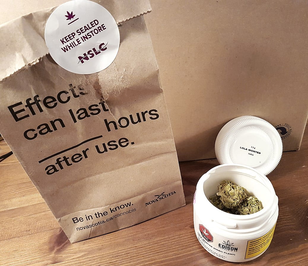 This photo shows an open 3.5 gram plastic canister of indica-dominant strain Lola Montes by the Edison Cannabis Co. and a brown paper bag from the Nova Scotia Liquor Corporation (NSLC) cannabis store in Halifax, Nova Scotia, Canada, after a purchase of legal recreational cannabis made on October 18, 2018.