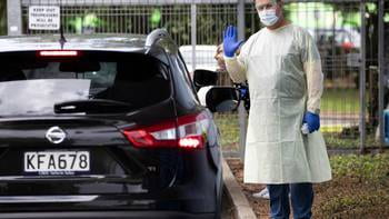 Man in PPE waves as he stands next to car
