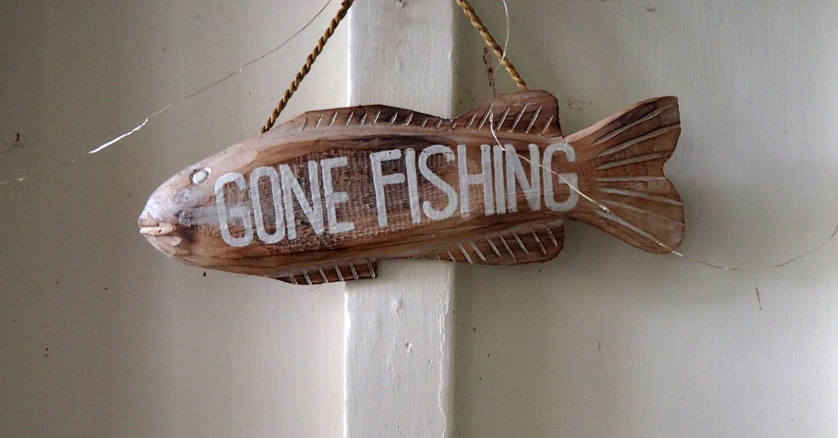 A wooden fish hanging ornament with the words 'gone fishing' painted on it
