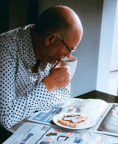 An old man eats sardines and drinks tea