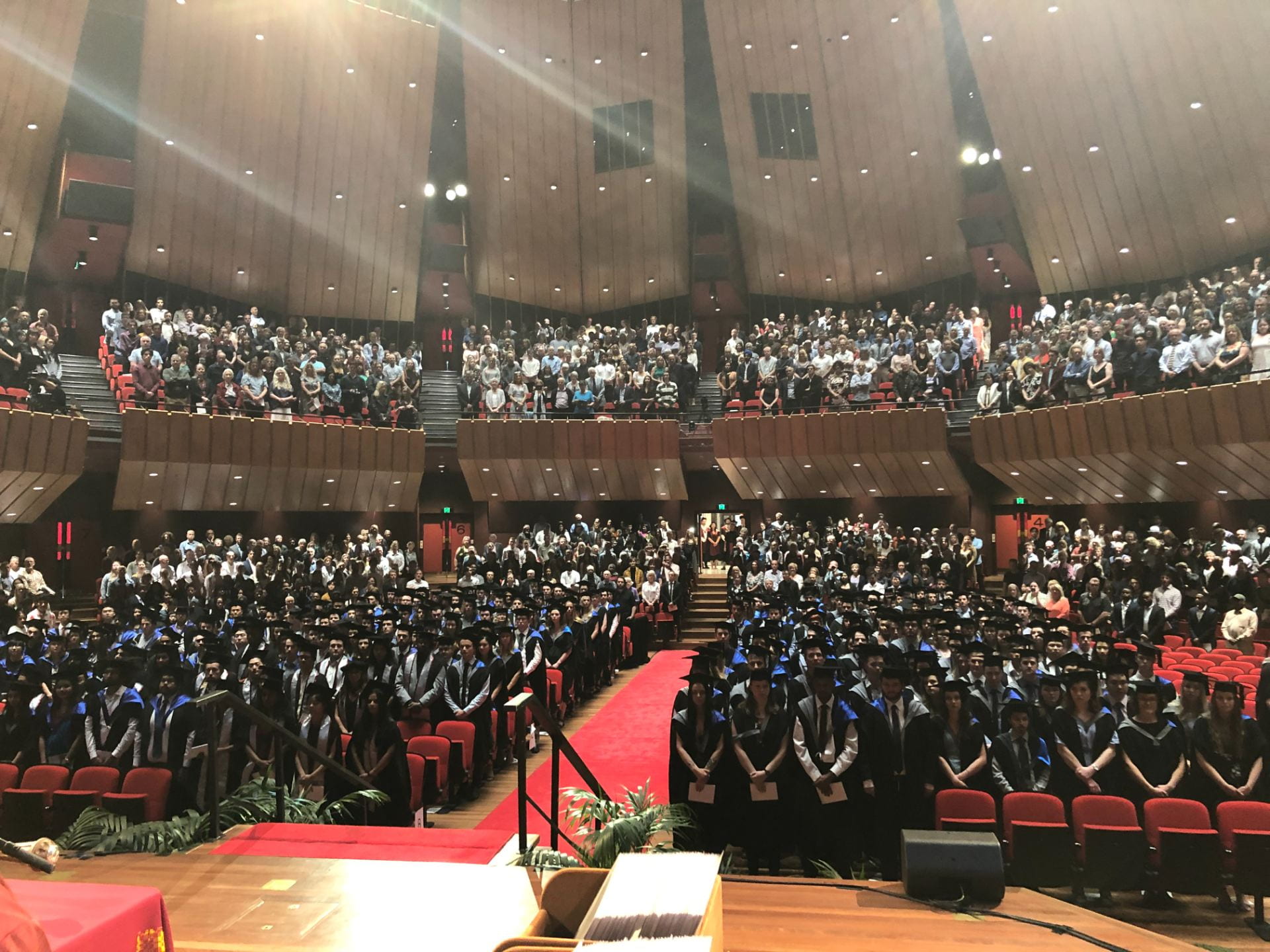 View from the stage of a crowded town hall filled with graduands and spectators
