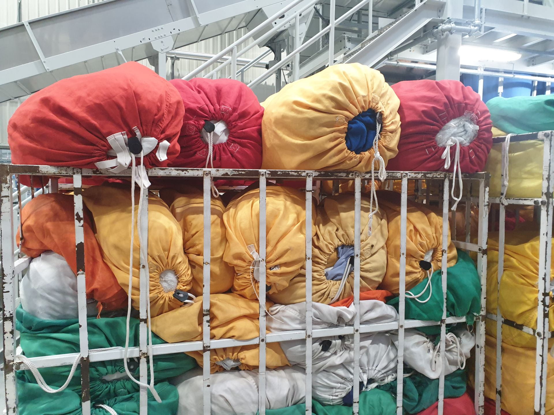 Coloured bags filled with dirty laundry stacked on a trolley